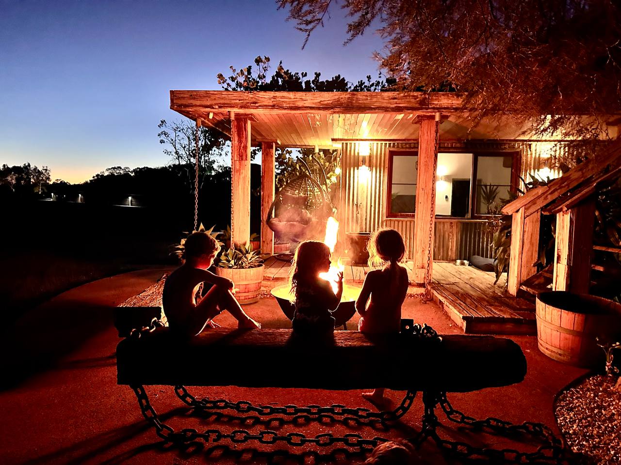 Three kids around campfire at dusk